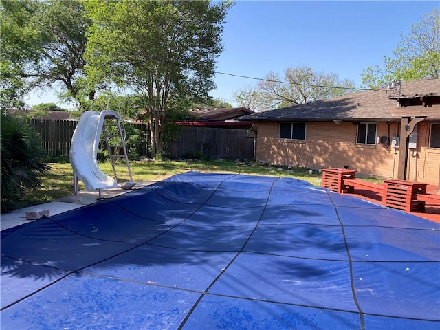 view of swimming pool featuring fence, a fenced in pool, and a water slide