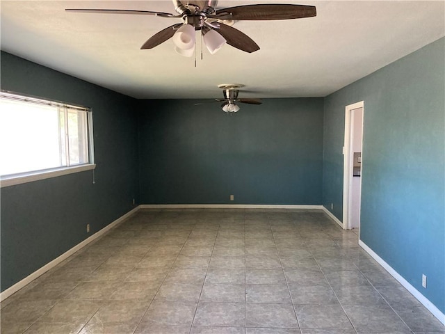 tiled empty room featuring baseboards and a ceiling fan