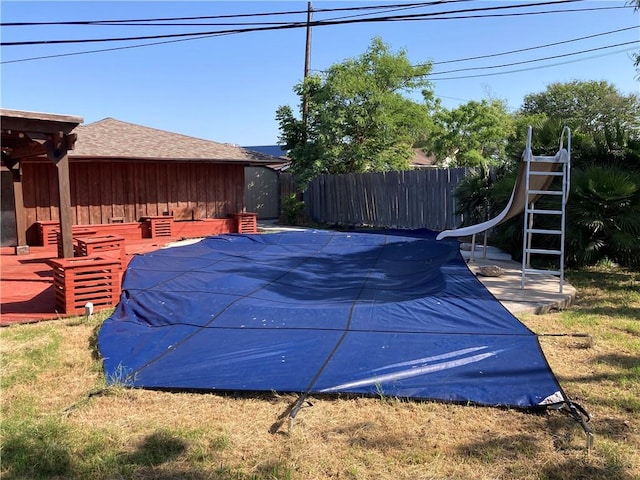 view of swimming pool featuring fence, a water slide, and a fenced in pool