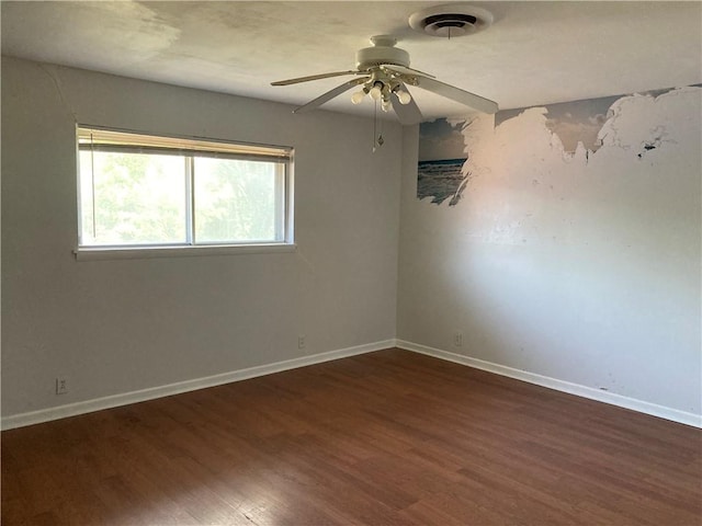 spare room featuring baseboards, ceiling fan, visible vents, and wood finished floors