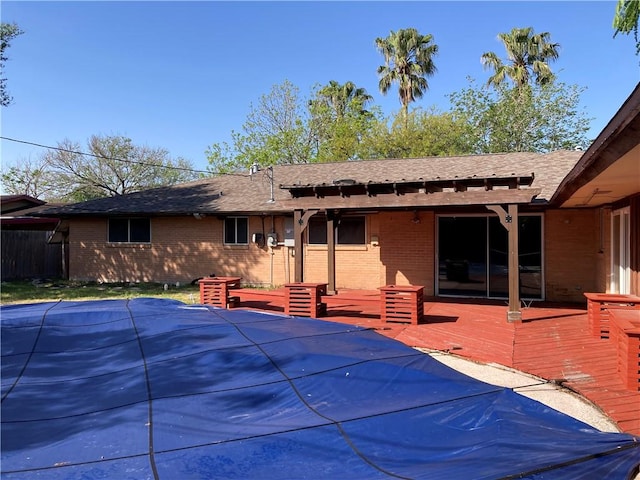 exterior space featuring brick siding, roof with shingles, and a deck