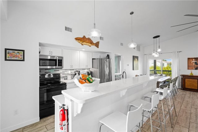 42 Nassau Dr, Rockport, TX 78382 - kitchen featuring stainless steel appliances, white cabinetry, decorative backsplash, a kitchen breakfast bar, and light wood finished floors