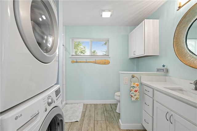 42 Nassau Dr, Rockport, TX 78382 - laundry room featuring stacked washing machine and dryer, healthy amount of natural light, light wood-type flooring, and baseboards
