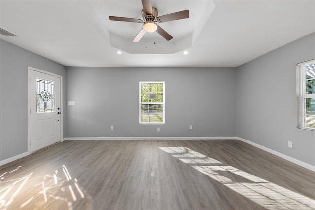 interior space with hardwood / wood-style floors, ceiling fan, and a tray ceiling