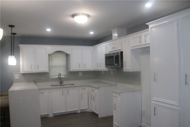 kitchen featuring sink, dark wood-type flooring, backsplash, decorative light fixtures, and white cabinets