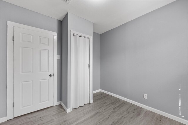 unfurnished bedroom with light hardwood / wood-style floors and a closet