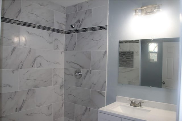 bathroom with tiled shower and vanity