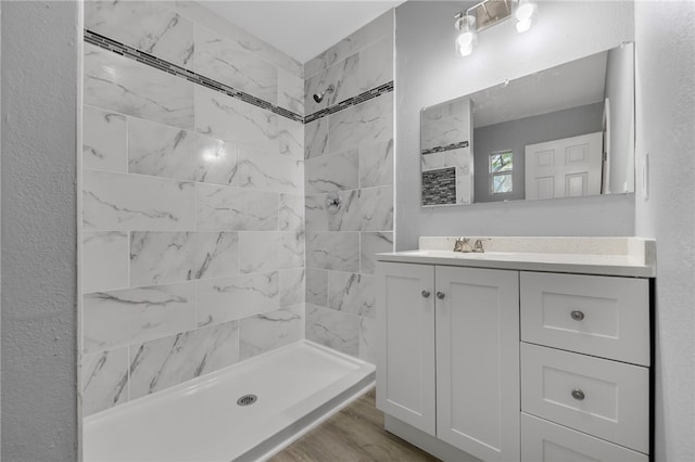 bathroom with tiled shower, vanity, and hardwood / wood-style flooring