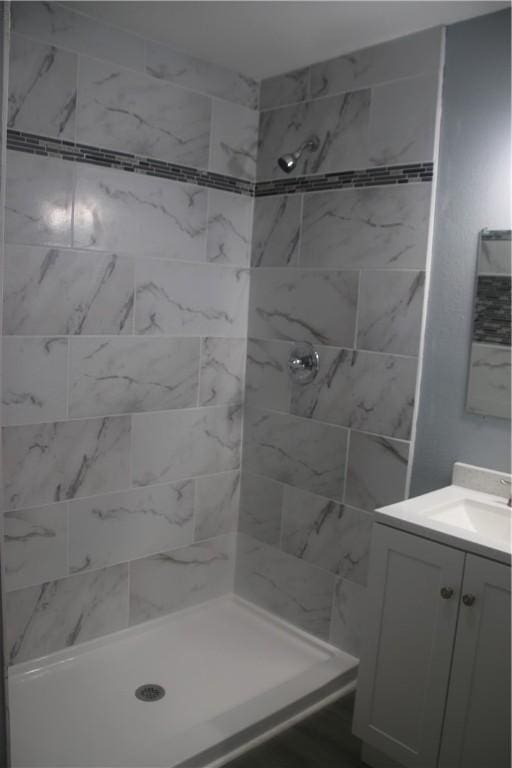 bathroom featuring tiled shower and vanity