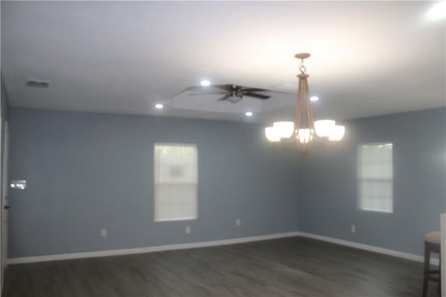 spare room with dark hardwood / wood-style floors and ceiling fan with notable chandelier