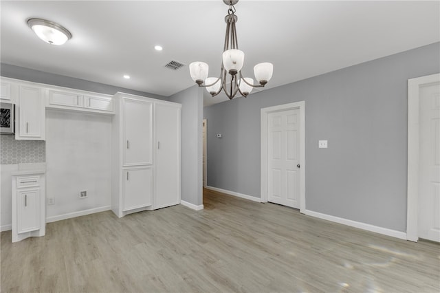 kitchen featuring decorative backsplash, decorative light fixtures, light hardwood / wood-style flooring, white cabinets, and a chandelier