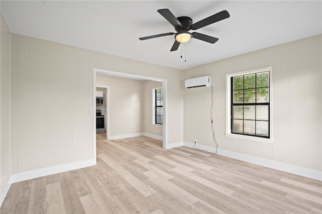 empty room with light wood-type flooring, a wall unit AC, and ceiling fan