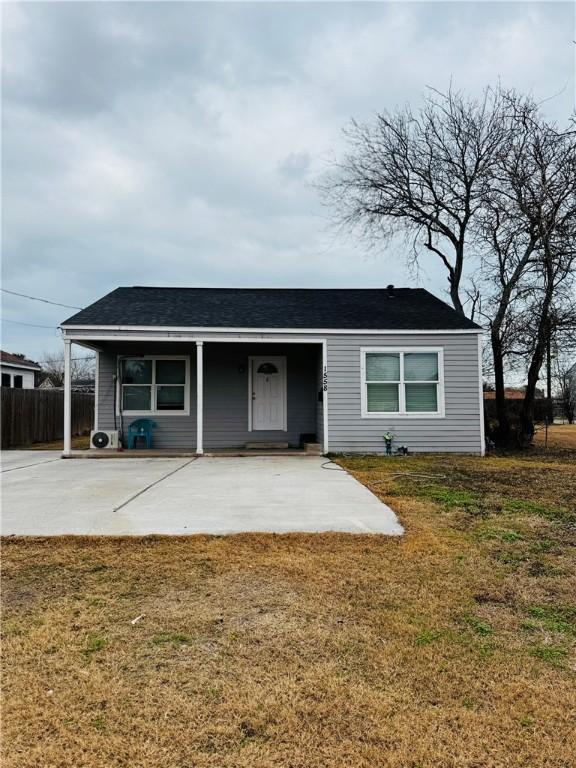 back of property featuring covered porch, roof with shingles, a yard, and fence