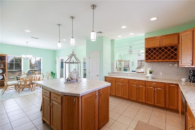 kitchen with a center island, backsplash, ceiling fan, decorative light fixtures, and light tile patterned flooring