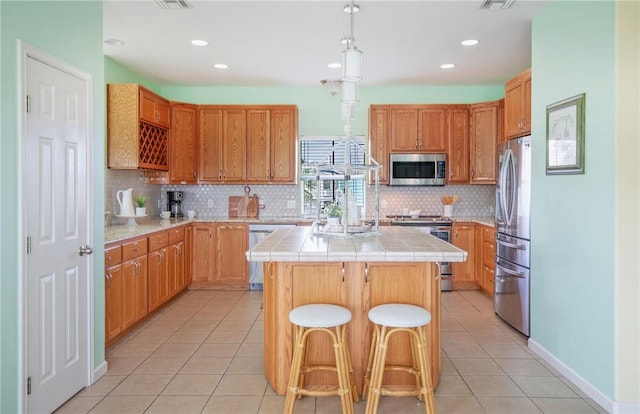 kitchen featuring a breakfast bar, appliances with stainless steel finishes, a center island, and light tile patterned floors