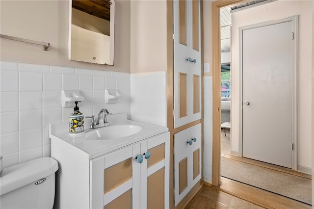 bathroom with toilet, vanity, wood-type flooring, and tile walls