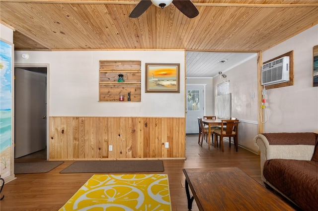 interior space featuring wood-type flooring, wooden walls, a wall mounted air conditioner, wooden ceiling, and ceiling fan