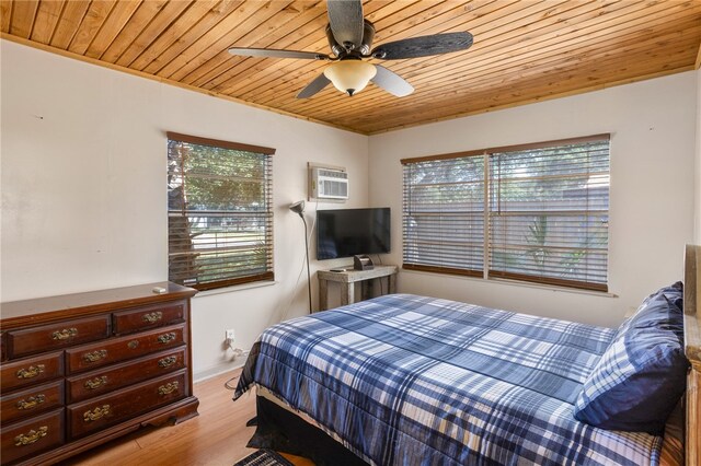 bedroom with a wall mounted air conditioner, wooden ceiling, ceiling fan, and light hardwood / wood-style flooring