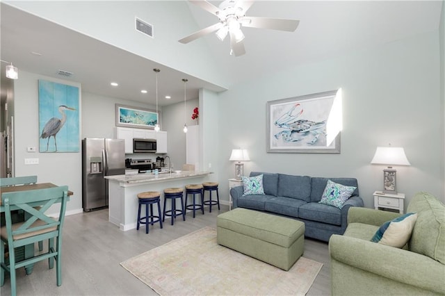 living room featuring ceiling fan, sink, and light wood-type flooring