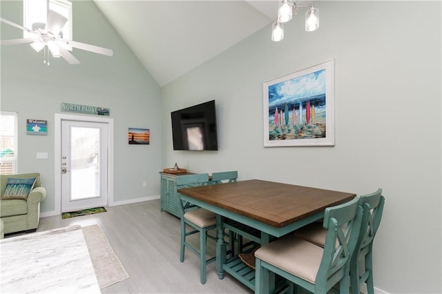 dining space with wood-type flooring, high vaulted ceiling, and ceiling fan