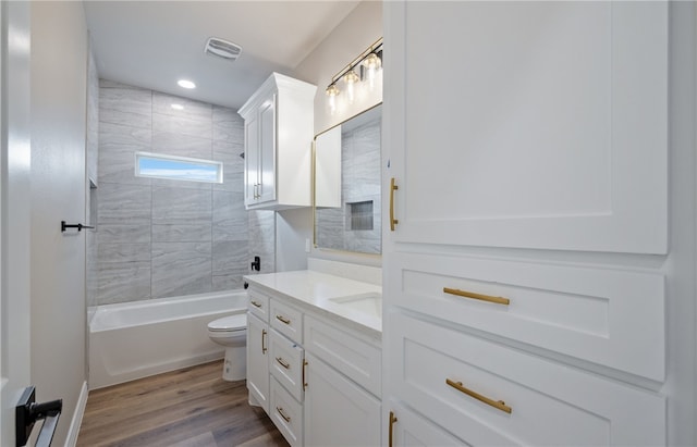 bathroom with toilet, wood finished floors, visible vents, vanity, and  shower combination