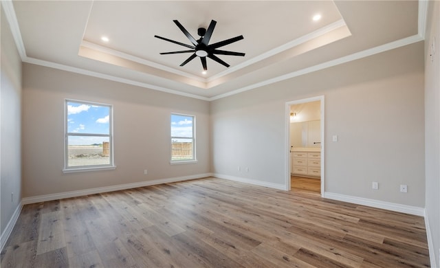 spare room featuring a raised ceiling, crown molding, light wood finished floors, and ceiling fan