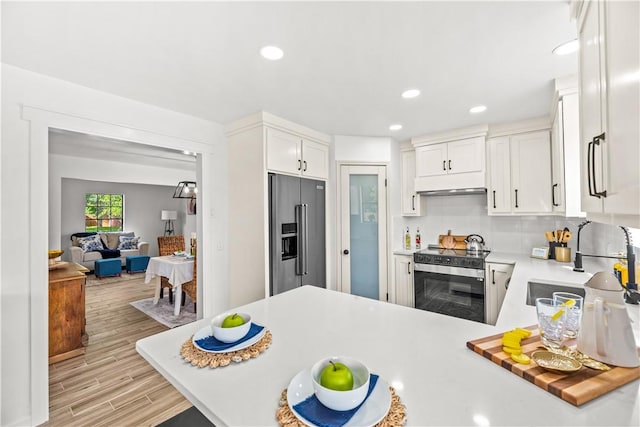 5025 Queens Ct, Corpus Christi, TX 78413 - kitchen featuring appliances with stainless steel finishes, light countertops, under cabinet range hood, white cabinets, and light wood-type flooring