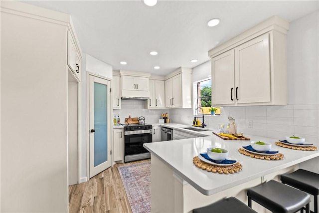 5025 Queens Ct, Corpus Christi, TX 78413 - kitchen with appliances with stainless steel finishes, a peninsula, light countertops, a breakfast bar area, and decorative backsplash