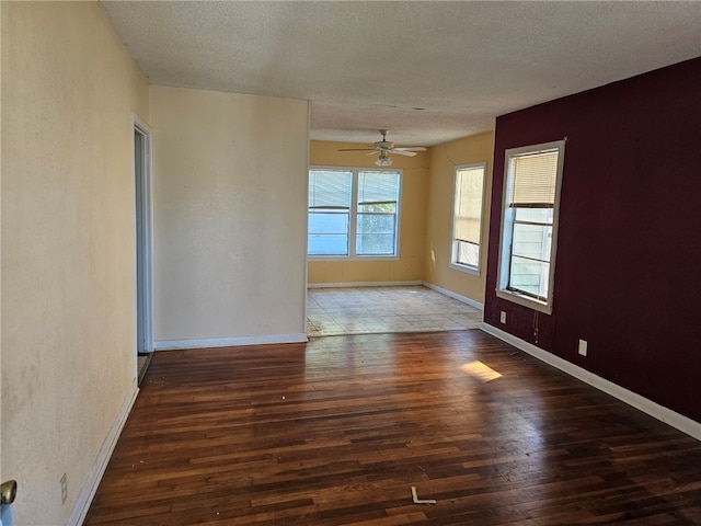 empty room with a textured ceiling, a ceiling fan, baseboards, and wood finished floors