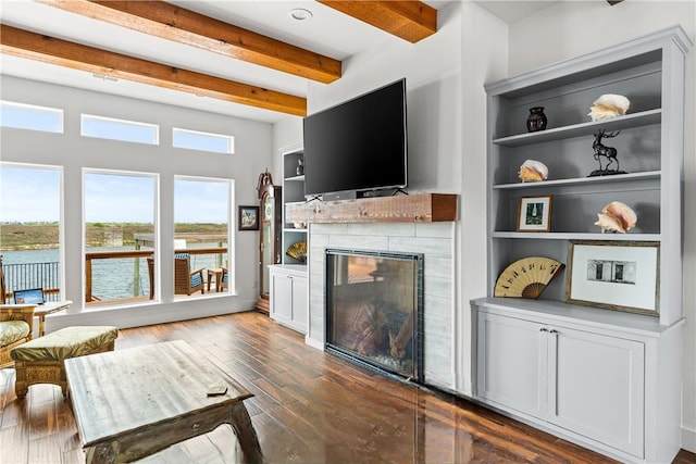 living area with dark wood-style floors, a tiled fireplace, and beam ceiling