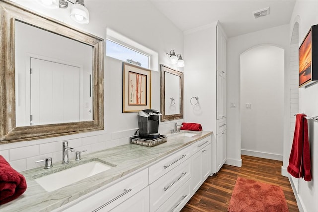 full bath with a sink, double vanity, wood finished floors, and visible vents
