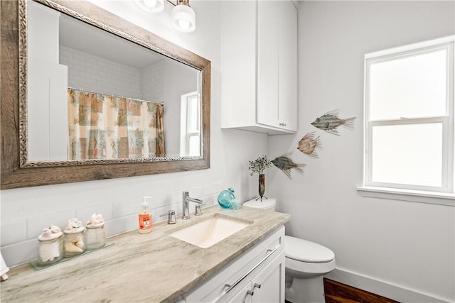 bathroom featuring plenty of natural light, tasteful backsplash, toilet, and vanity