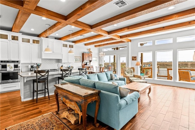 living area with beam ceiling, dark wood finished floors, recessed lighting, visible vents, and coffered ceiling