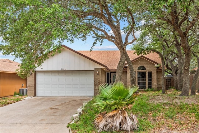 view of front of property with central AC, brick siding, a shingled roof, an attached garage, and driveway