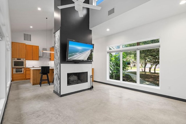 110 Forest Hls, Rockport, TX 78382 - unfurnished living room with a towering ceiling, concrete flooring, a ceiling fan, baseboards, and a fireplace
