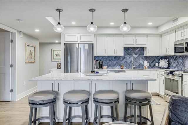 kitchen featuring white cabinetry, appliances with stainless steel finishes, a center island, and decorative light fixtures