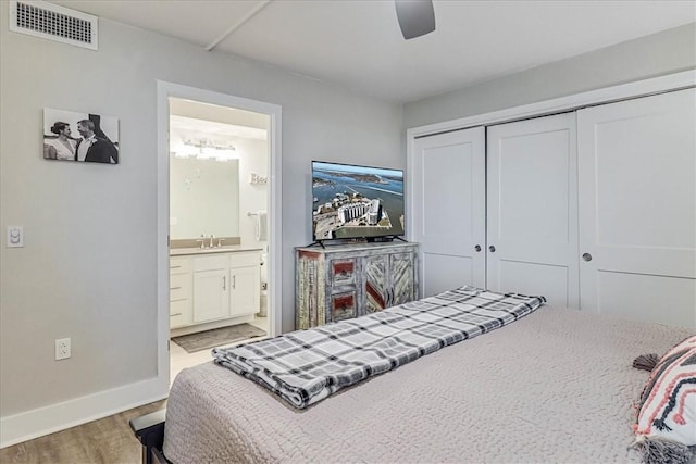 bedroom featuring hardwood / wood-style floors, connected bathroom, sink, ceiling fan, and a closet