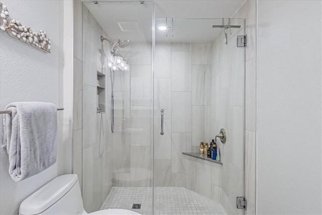 bathroom with a shower with door and toilet