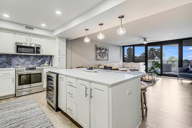 kitchen with backsplash, decorative light fixtures, white cabinets, and appliances with stainless steel finishes