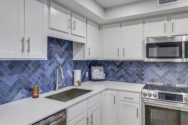 kitchen featuring white cabinetry, appliances with stainless steel finishes, sink, and backsplash