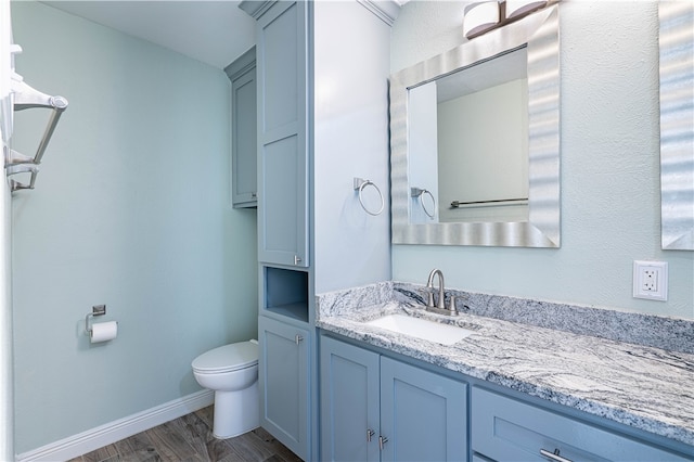 bathroom with toilet, vanity, and hardwood / wood-style floors