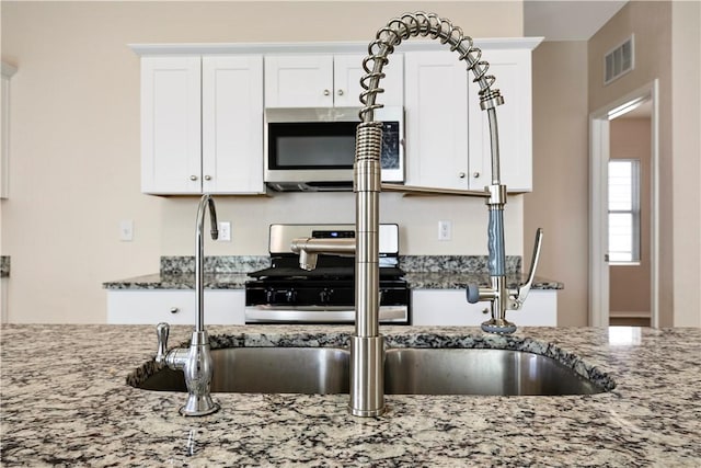 kitchen featuring white cabinets, light stone counters, and stainless steel appliances