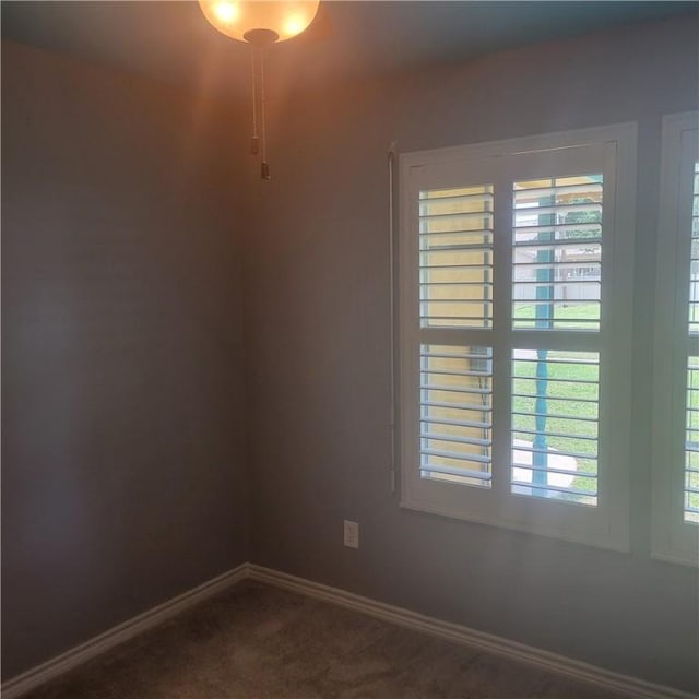 spare room featuring baseboards and dark colored carpet