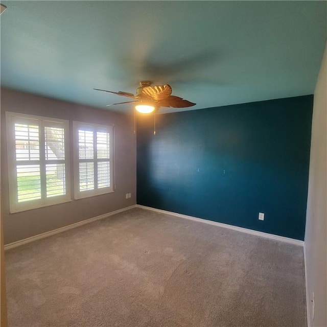 empty room with ceiling fan, carpet, and baseboards