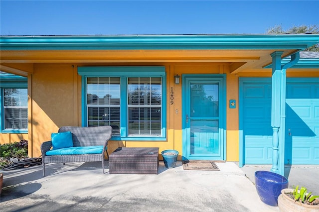 entrance to property with a garage and stucco siding