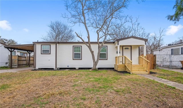 manufactured / mobile home with a carport, fence, and a front lawn