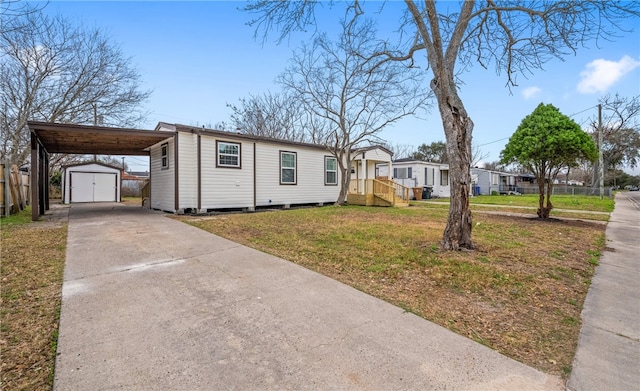 manufactured / mobile home with an attached carport, an outdoor structure, driveway, a storage unit, and a front lawn