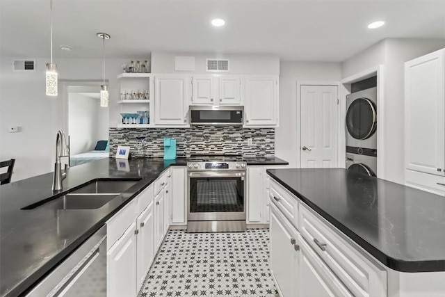 5973 State Highway 361 Unit 436, Port Aransas, TX 78373 - kitchen with stainless steel appliances, stacked washer and clothes dryer, dark countertops, open shelves, and white cabinets