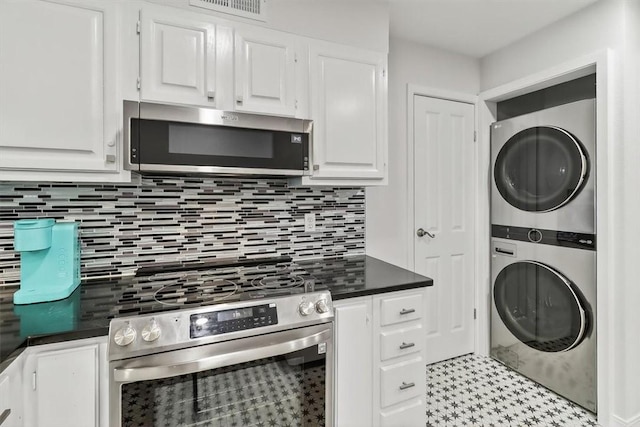 5973 State Highway 361 Unit 436, Port Aransas, TX 78373 - kitchen featuring appliances with stainless steel finishes, estacked washer and dryer, dark countertops, white cabinets, and tasteful backsplash