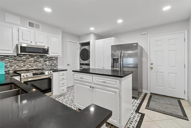 5973 State Highway 361 Unit 436, Port Aransas, TX 78373 - kitchen featuring appliances with stainless steel finishes, stacked washer and clothes dryer, dark countertops, white cabinetry, and recessed lighting